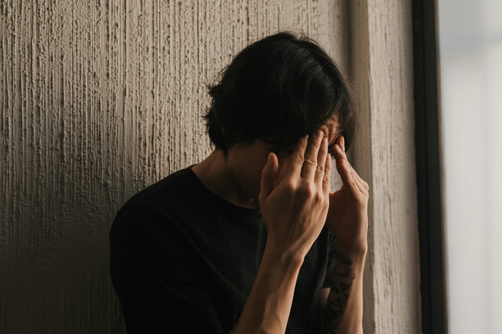 在效率至上的壓力下,一個男人感到工作倦怠,將頭埋在手裡反思。
